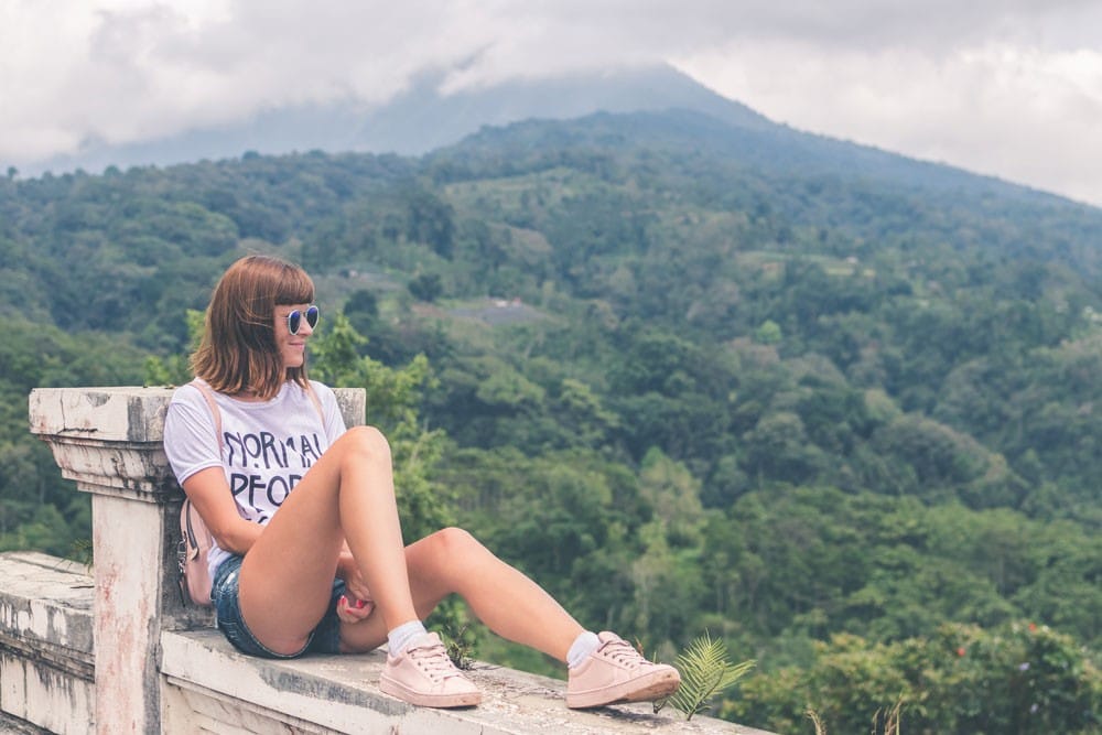 Entrevista trabajo chica morena con gafas sentada y mirando la vegetación